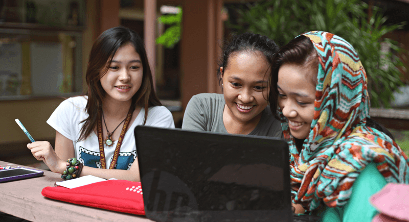 Students smiling at the laptop.
